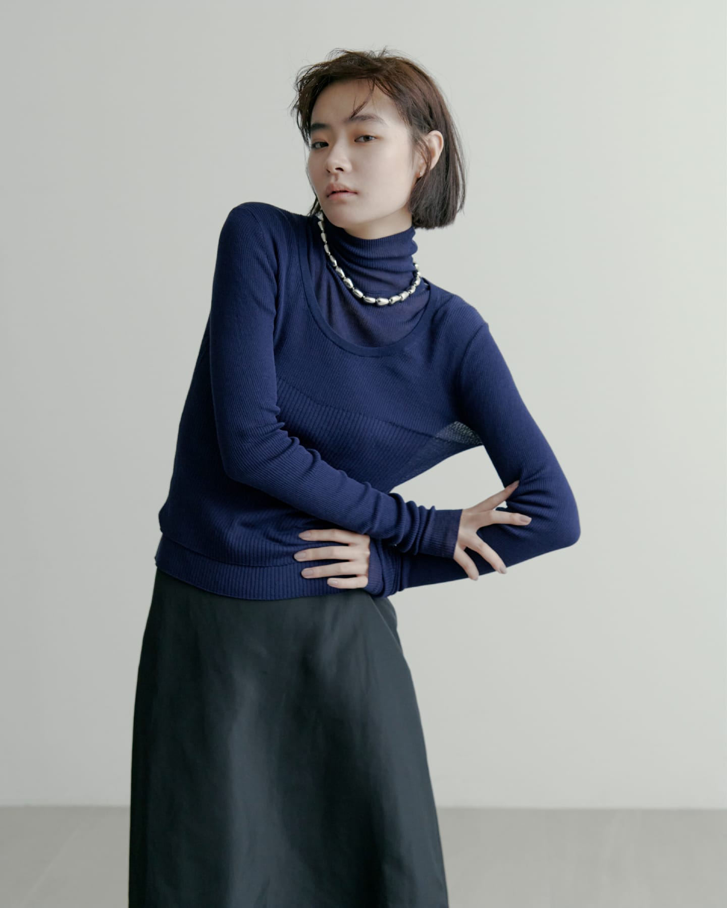 washableタートルシアーリブニット＆washableUネックシアーリブニット＆コンフォートフレアタフタSK＆TWISTBEADSNECKLACEを着た女性
