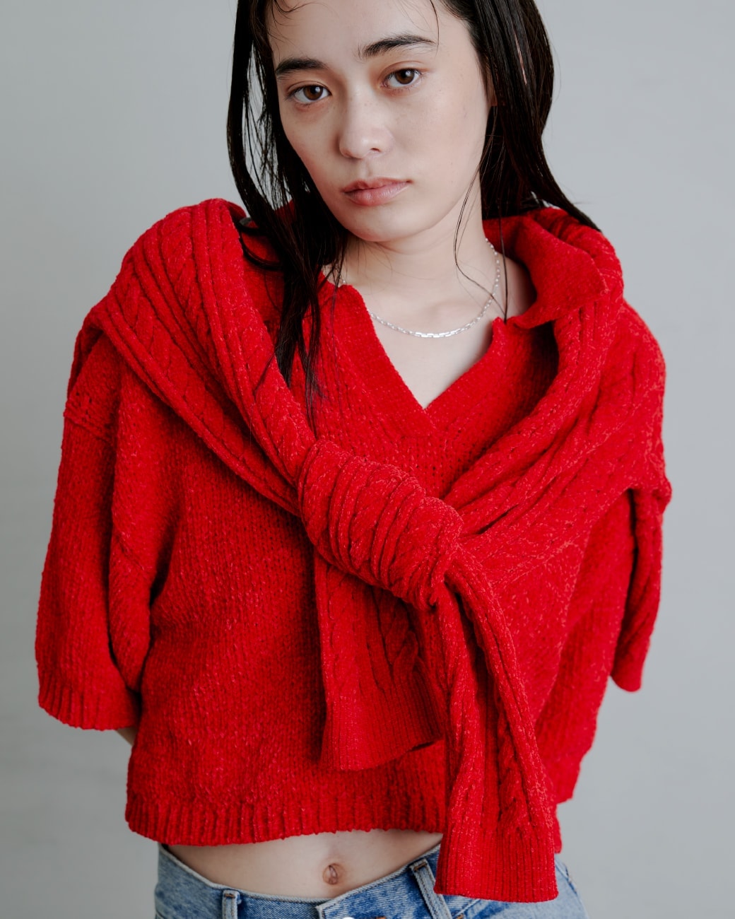 赤いトップスを着た女性が斜め下を向いている画像