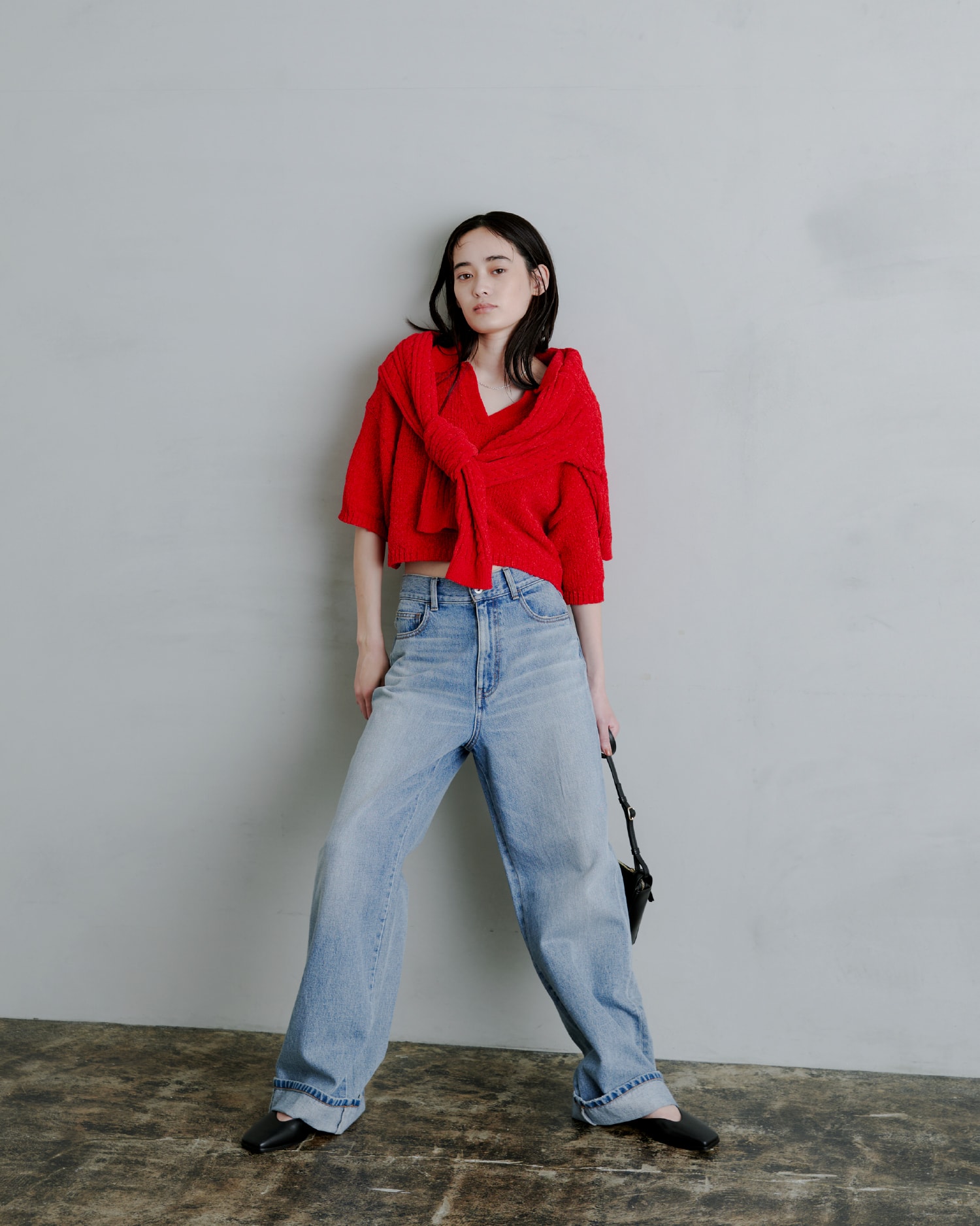 赤いトップスを着た女性が斜め下を向いている画像