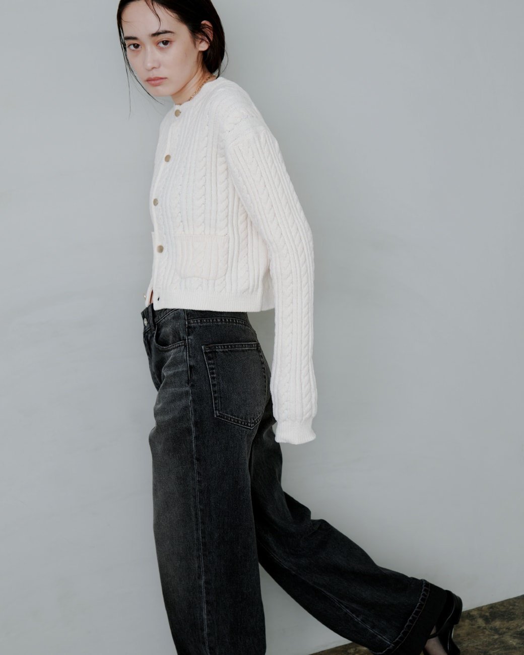 白いニットに黒いパンツを着た女性が正面を向いている画像