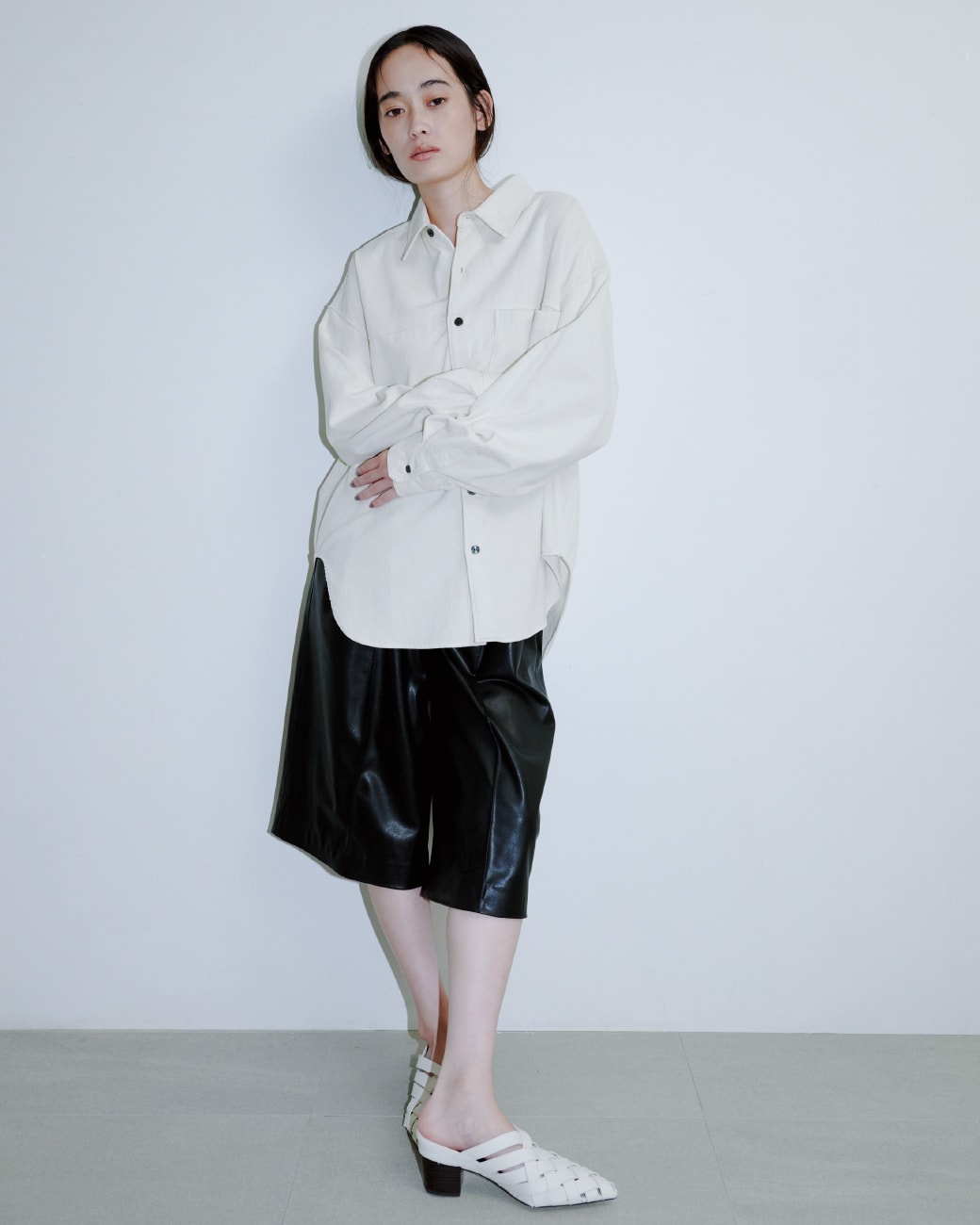 白いシャツに黒いパンツを着た女性が正面を向いている画像