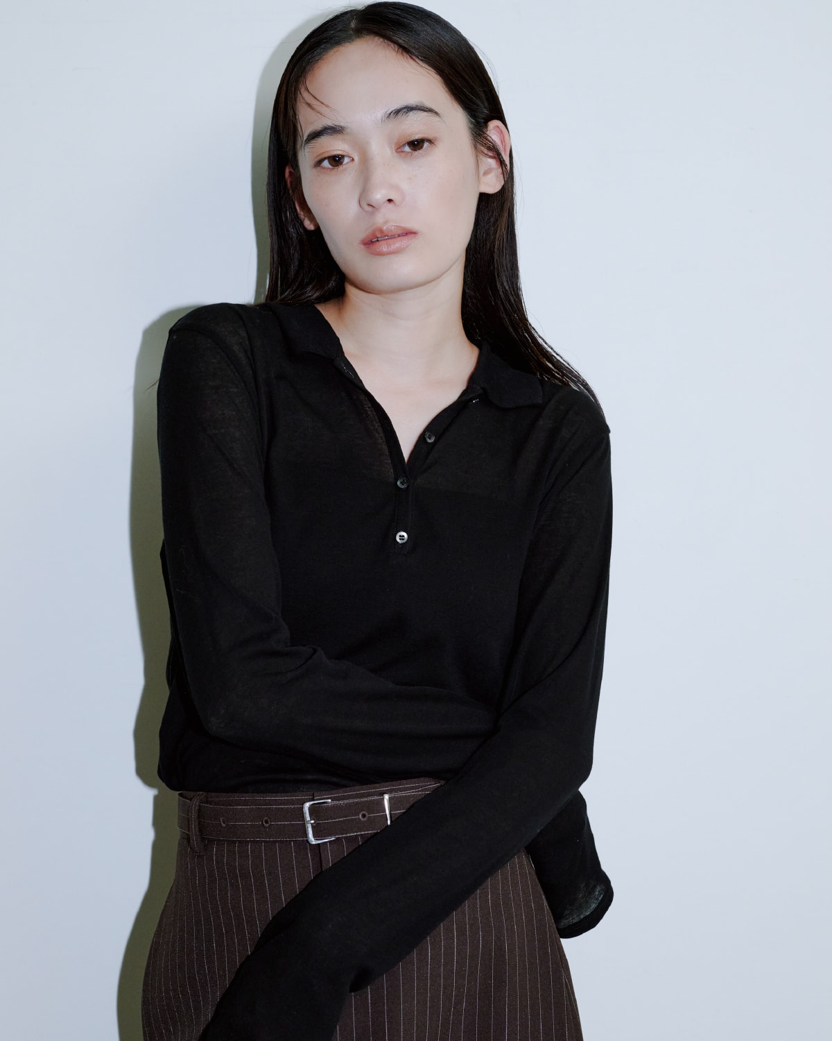 黒いシャツにブラウンのロングスカートを着た女性が正面を向いている画像