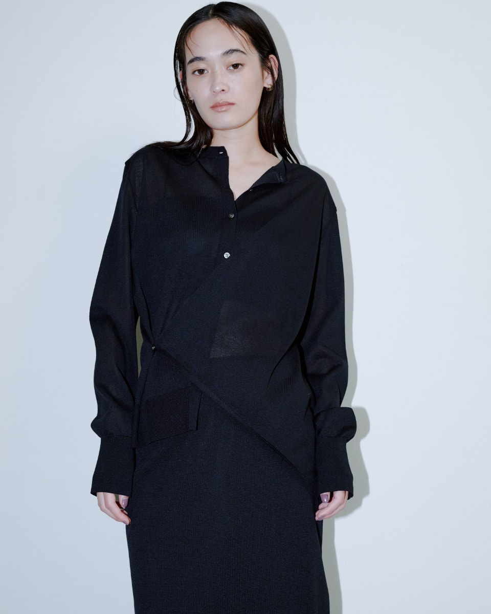 黒いトップスに黒いパンツを着た女性が正面を向いている画像