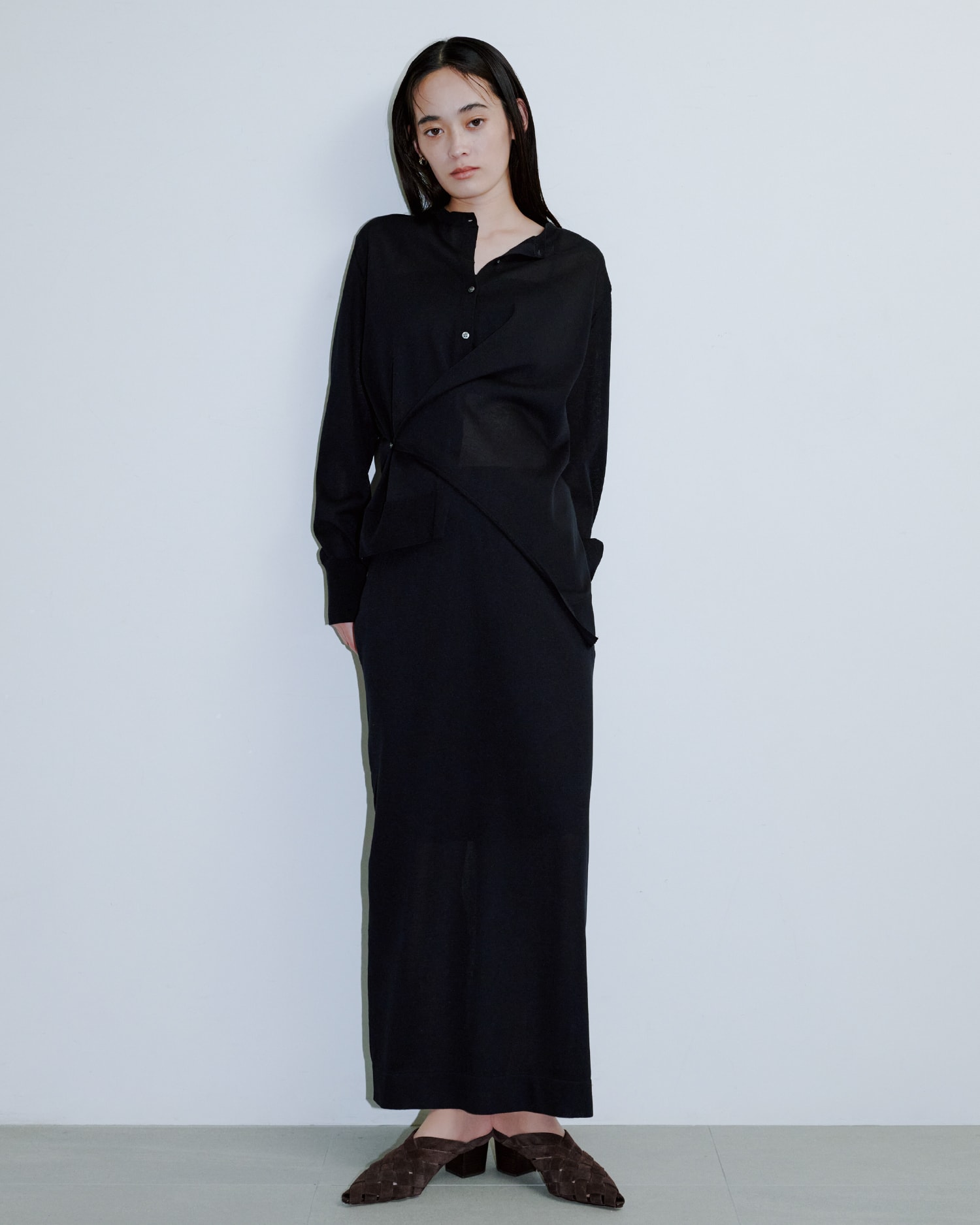 黒いトップスに黒いパンツを着た女性が正面を向いている画像