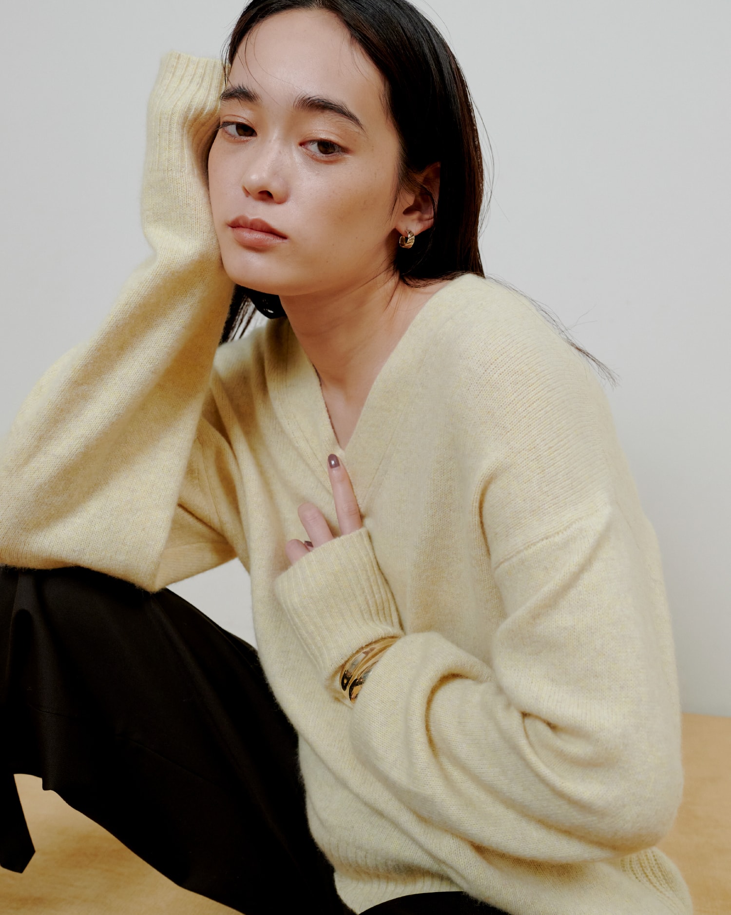 黄色いニットに黒いパンツを着た女性が正面を向いている画像
