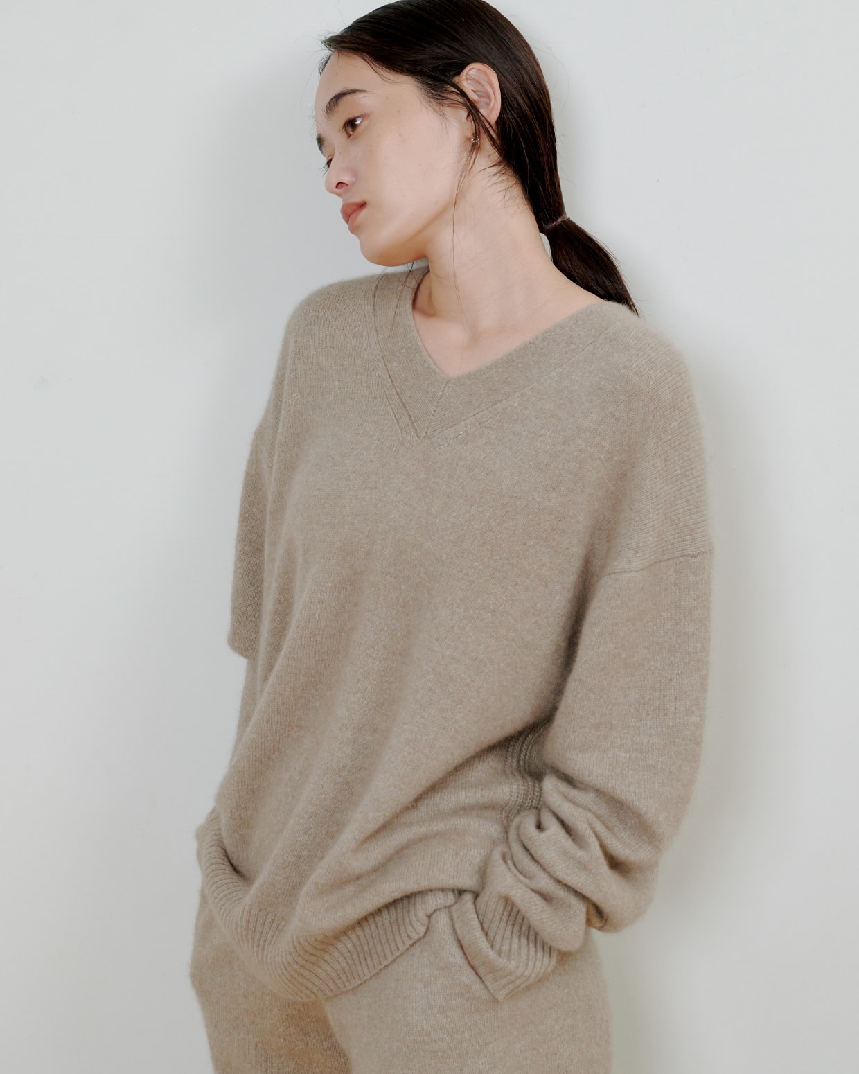 ベージュのニットにベージュのパンツを着た女性が正面を向いている画像