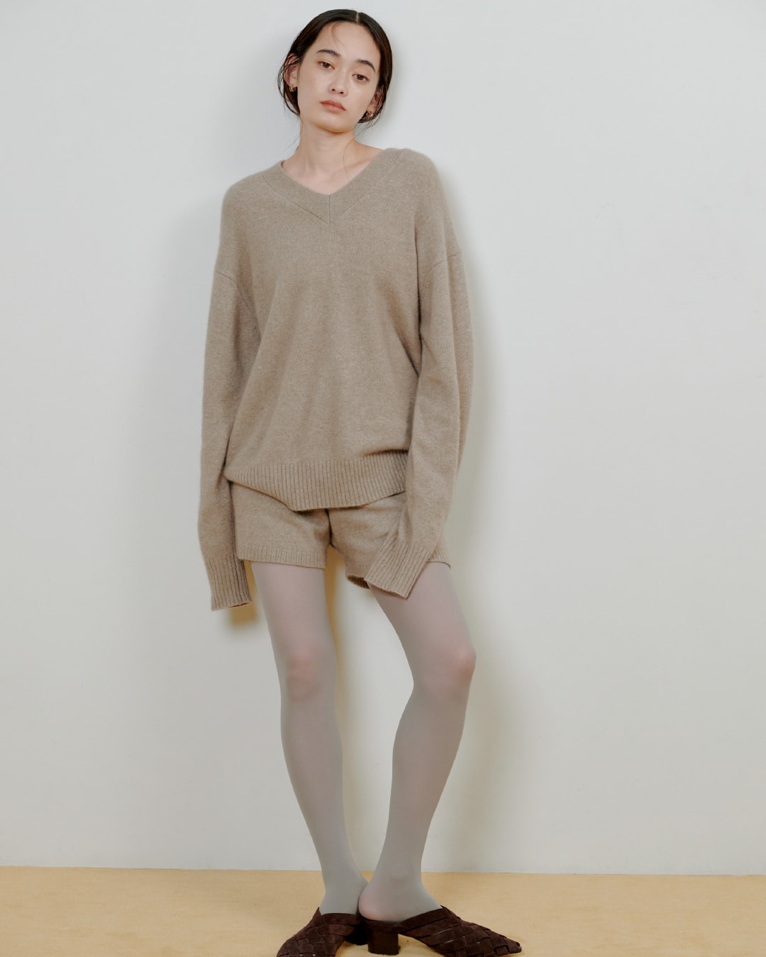 ベージュのニットにベージュのパンツを着た女性が正面を向いている画像