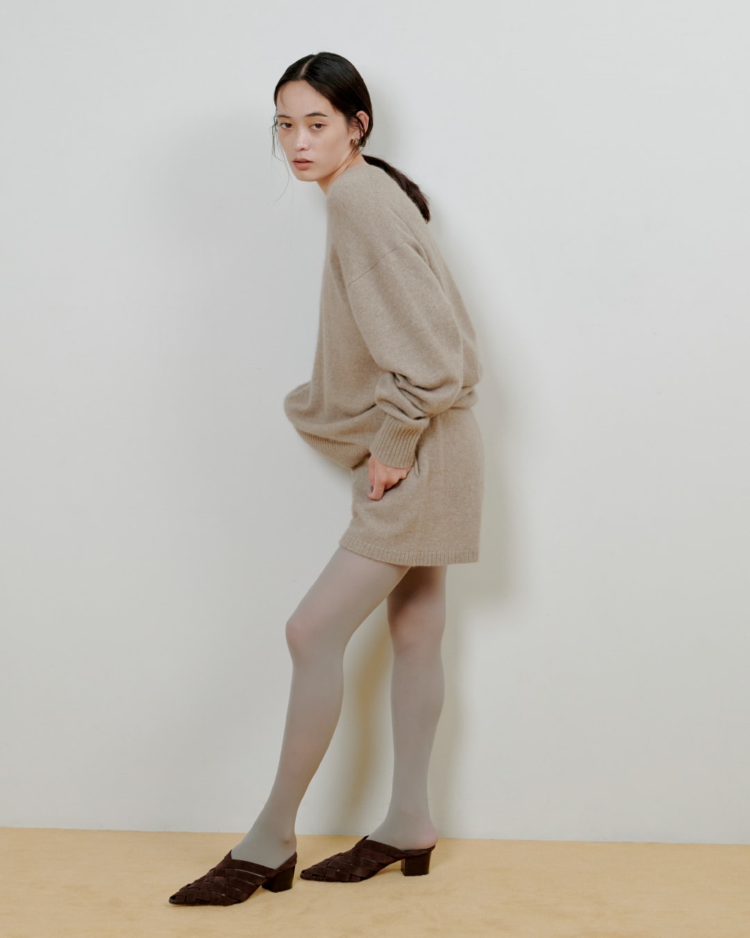 ベージュのニットにベージュのパンツを着た女性が正面を向いている画像