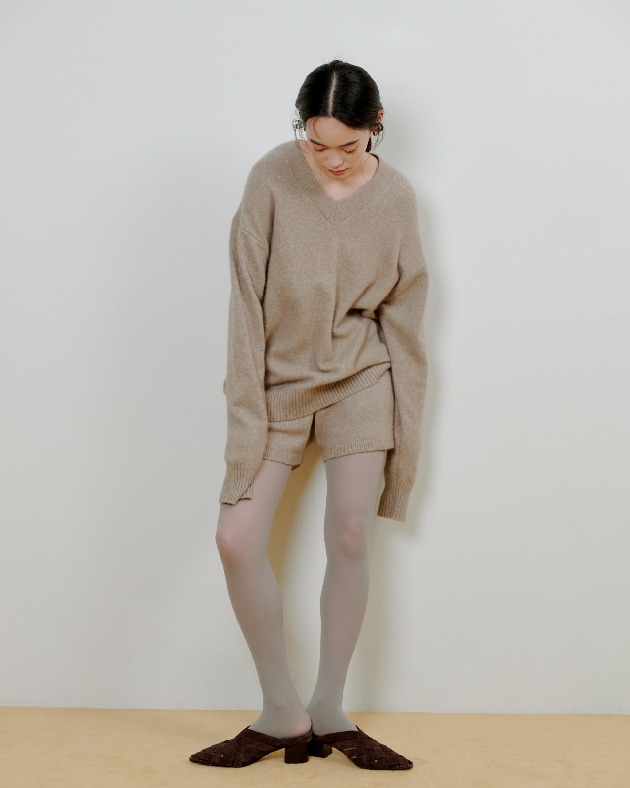 ベージュのニットにベージュのパンツを着た女性が正面を向いている画像