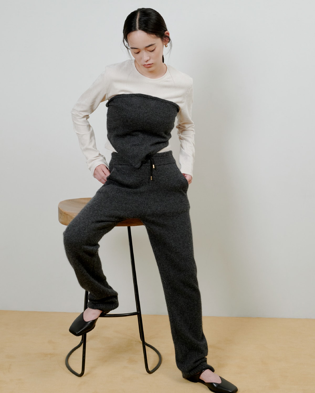 グレーのニットにグレーのパンツを着た女性が正面を向いている画像