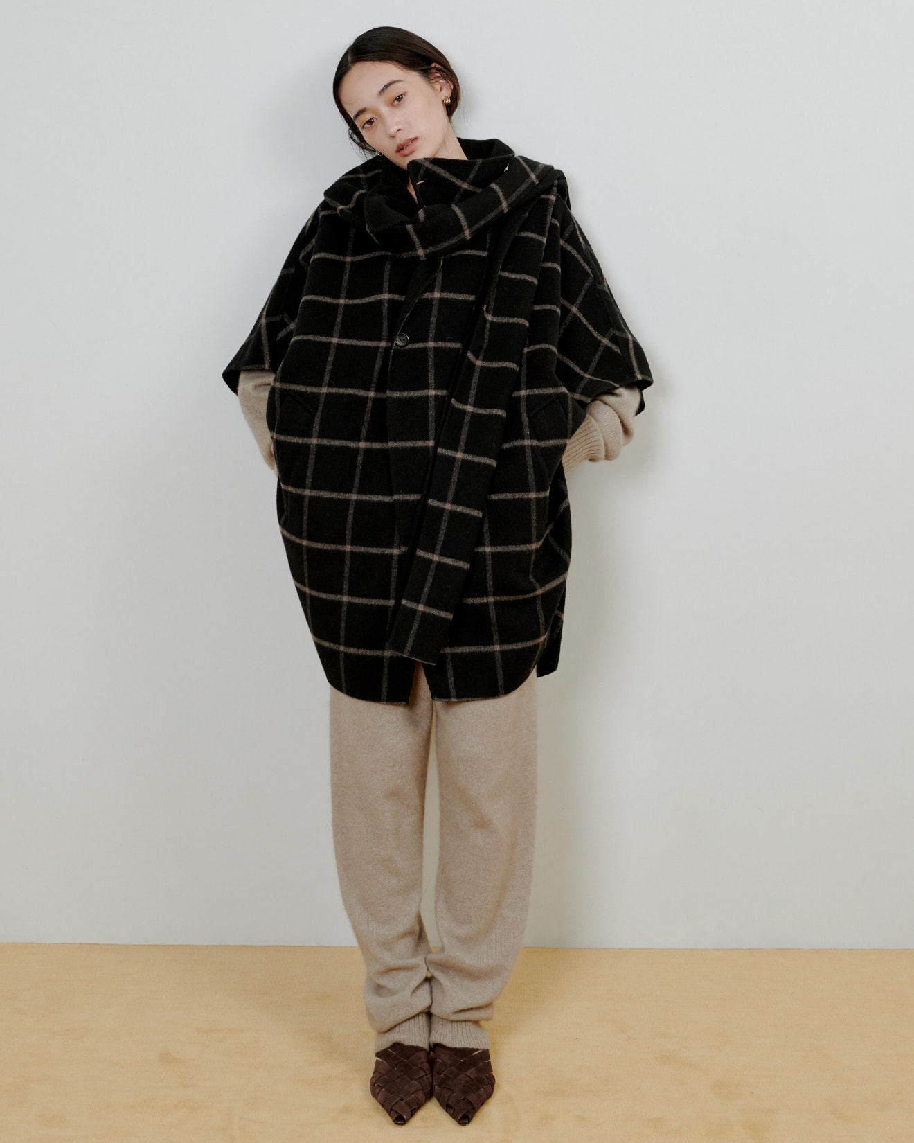 チェックのシャツに黒いパンツを着た女性が正面を向いている画像