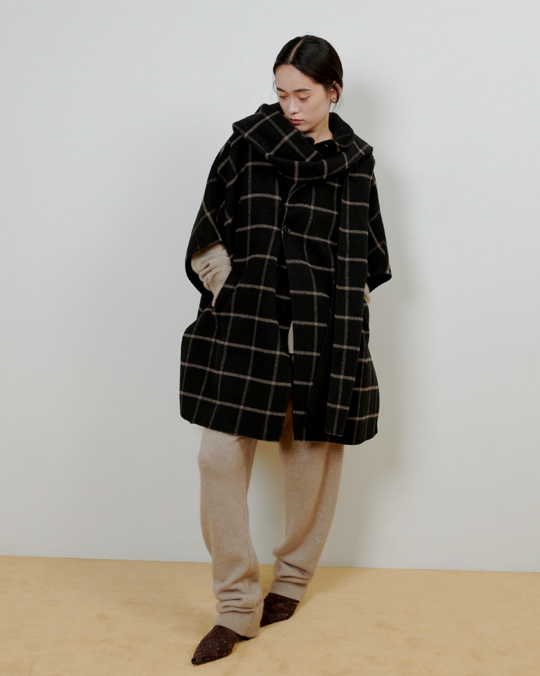 チェックのシャツに黒いパンツを着た女性が正面を向いている画像