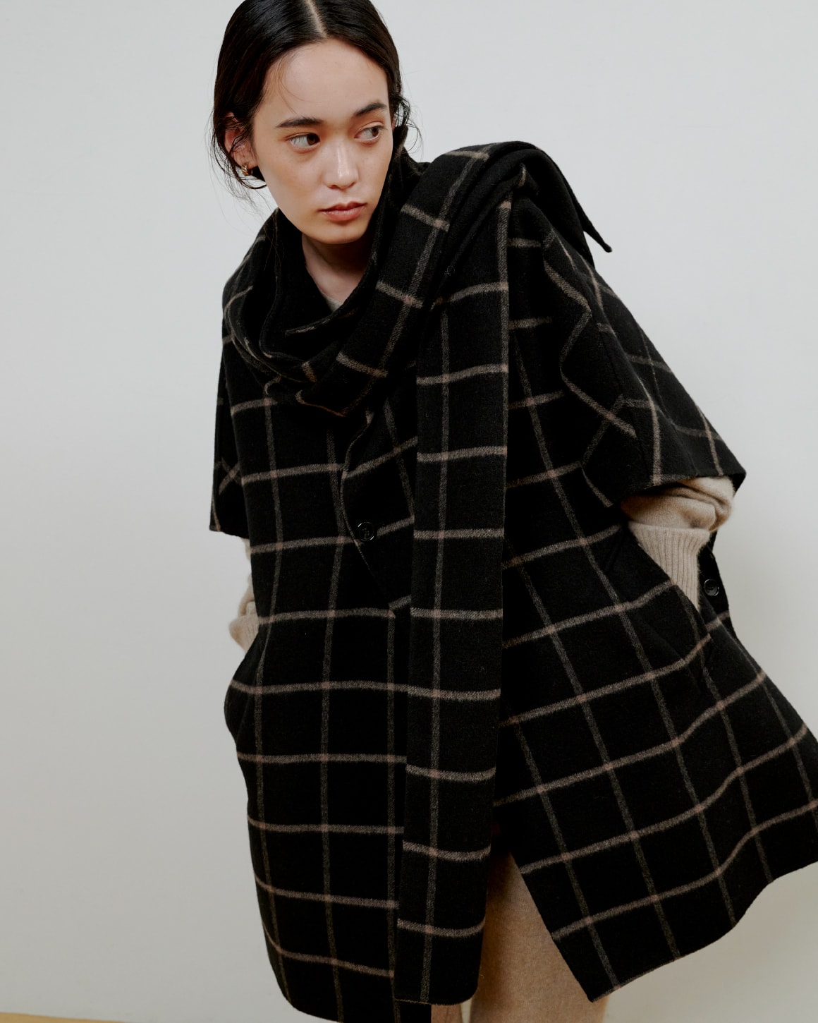 チェックのシャツに黒いパンツを着た女性が正面を向いている画像