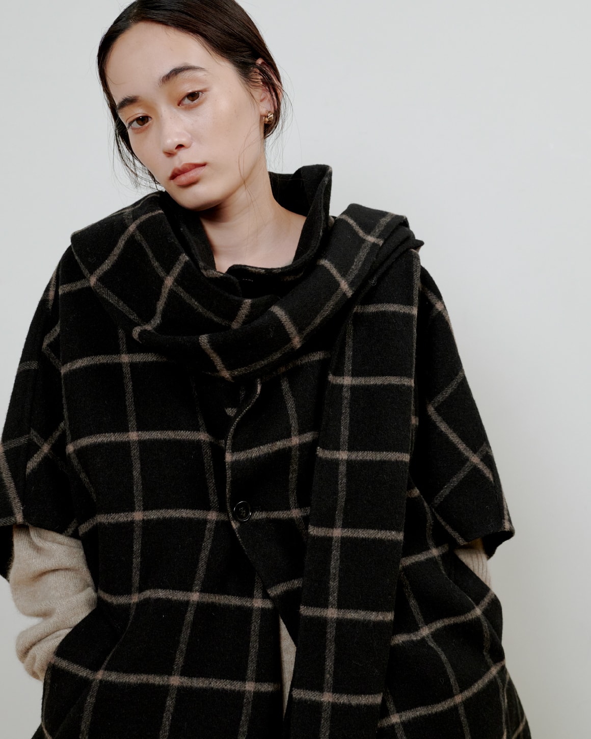 チェックのシャツに黒いパンツを着た女性が正面を向いている画像