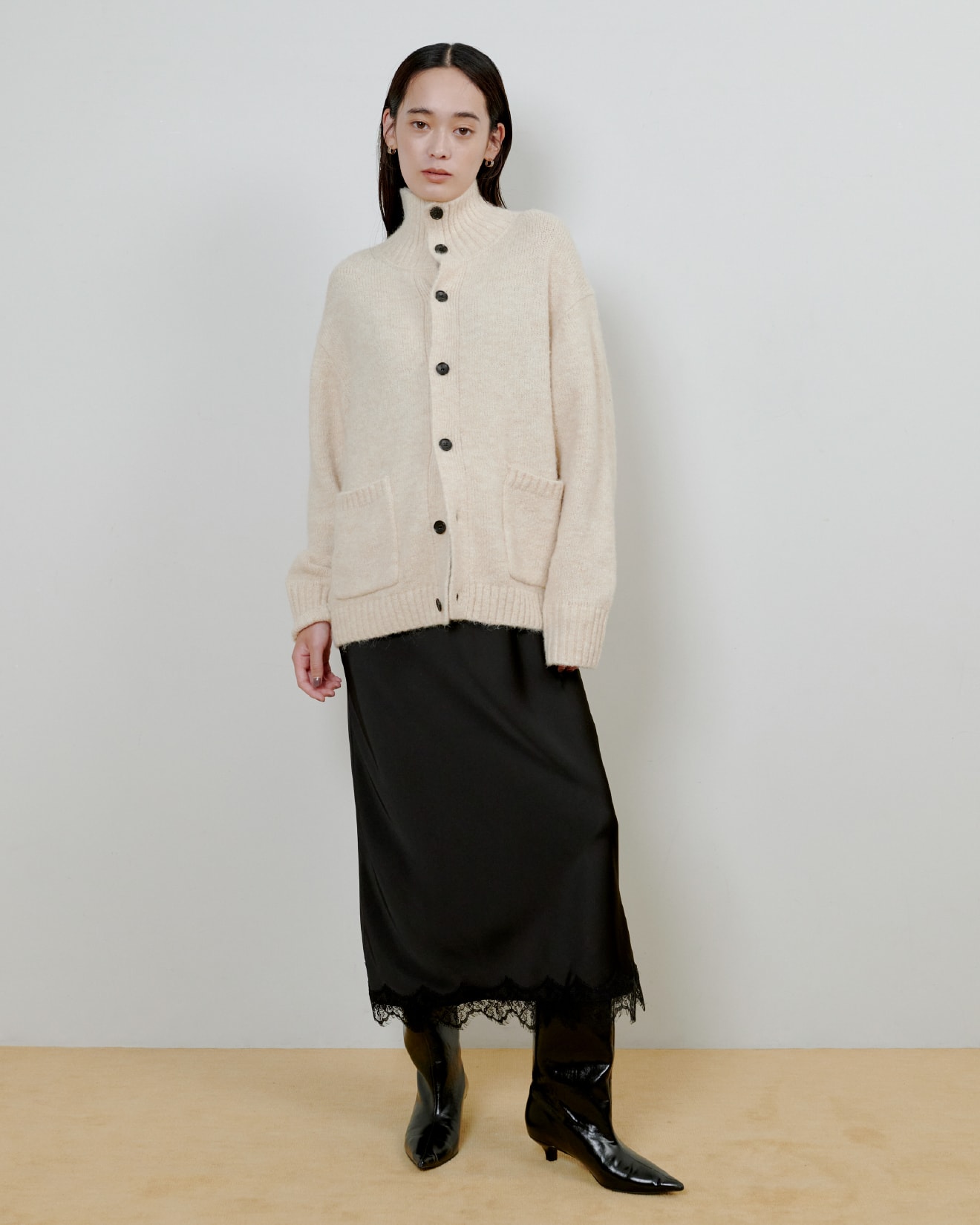 ベージュのニットに黒いスカートを着た女性が正面を向いている画像
