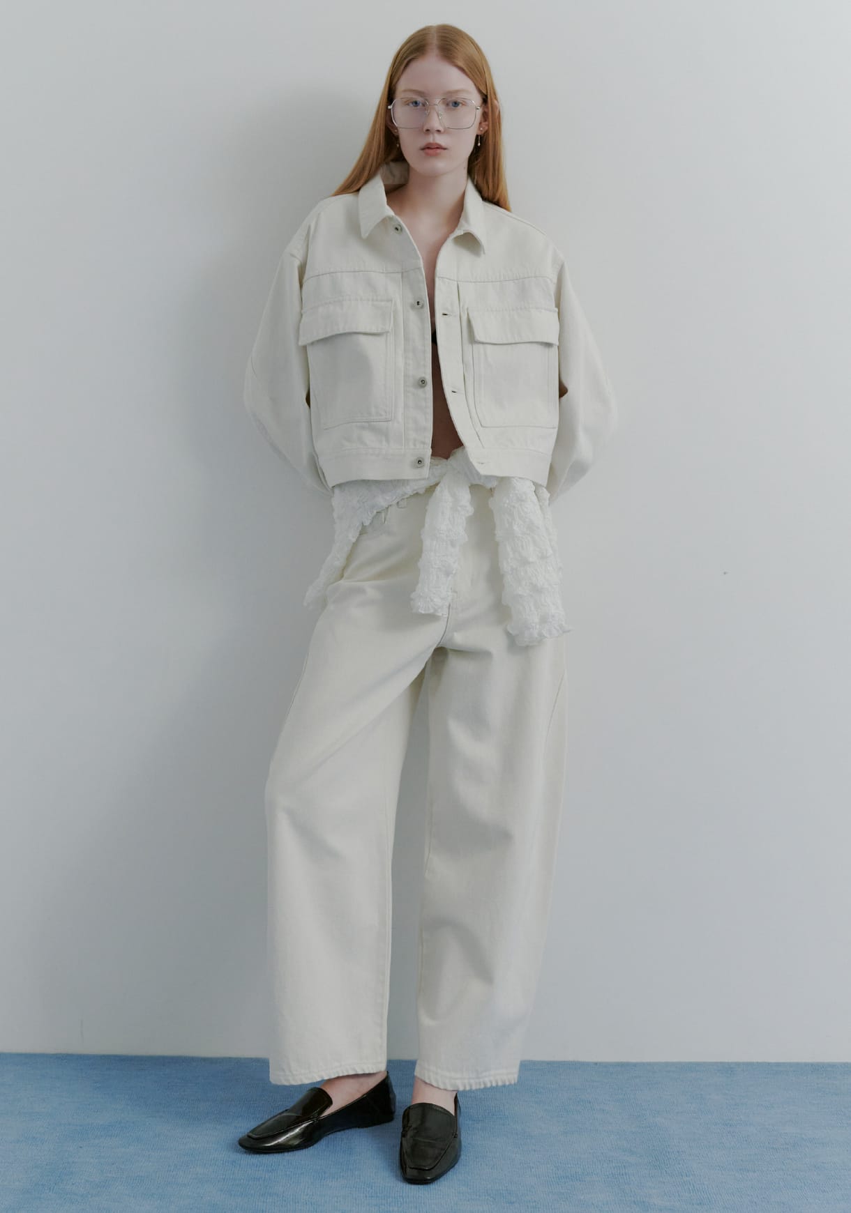 ミドルカットデニムジャケット&シャーリングＶネックカーデ&ハイフォルムコクーンデニム&レザートングストラップサンダルを着用した女性