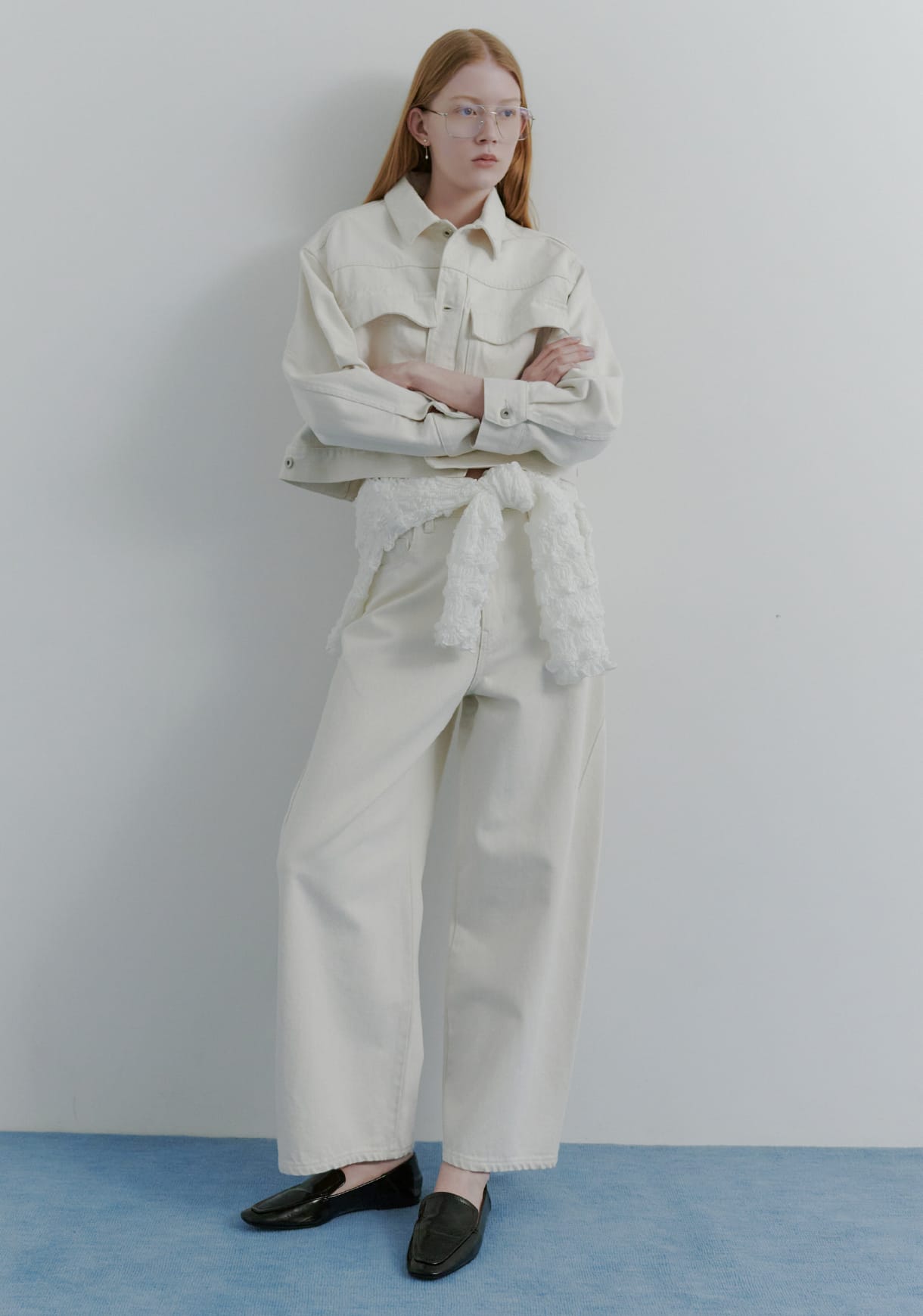 ミドルカットデニムジャケット&シャーリングＶネックカーデ&ハイフォルムコクーンデニム&レザートングストラップサンダルを着用した女性