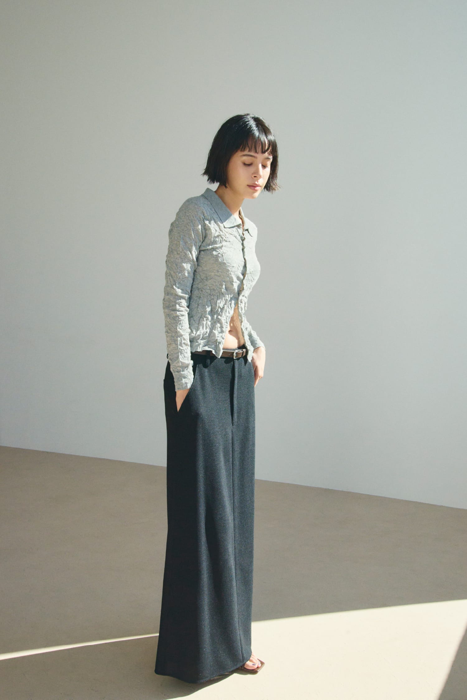 ワッシャーニットシャツ&からみ織りセミフレアスカート&レザートングストラップサンダル&レザーベルトを着用した女性