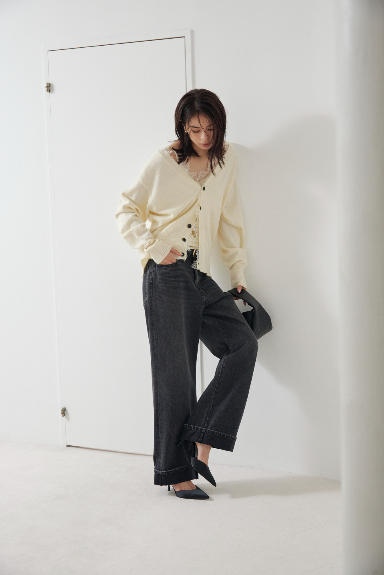 Look02 白のカーディガンとデニムパンツでドアの前に立つ着用カット